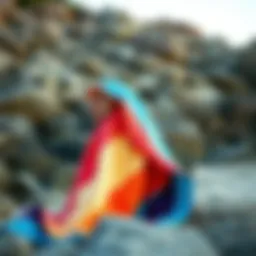 A stylish towel poncho in vibrant colors draped over a rocky beach setting